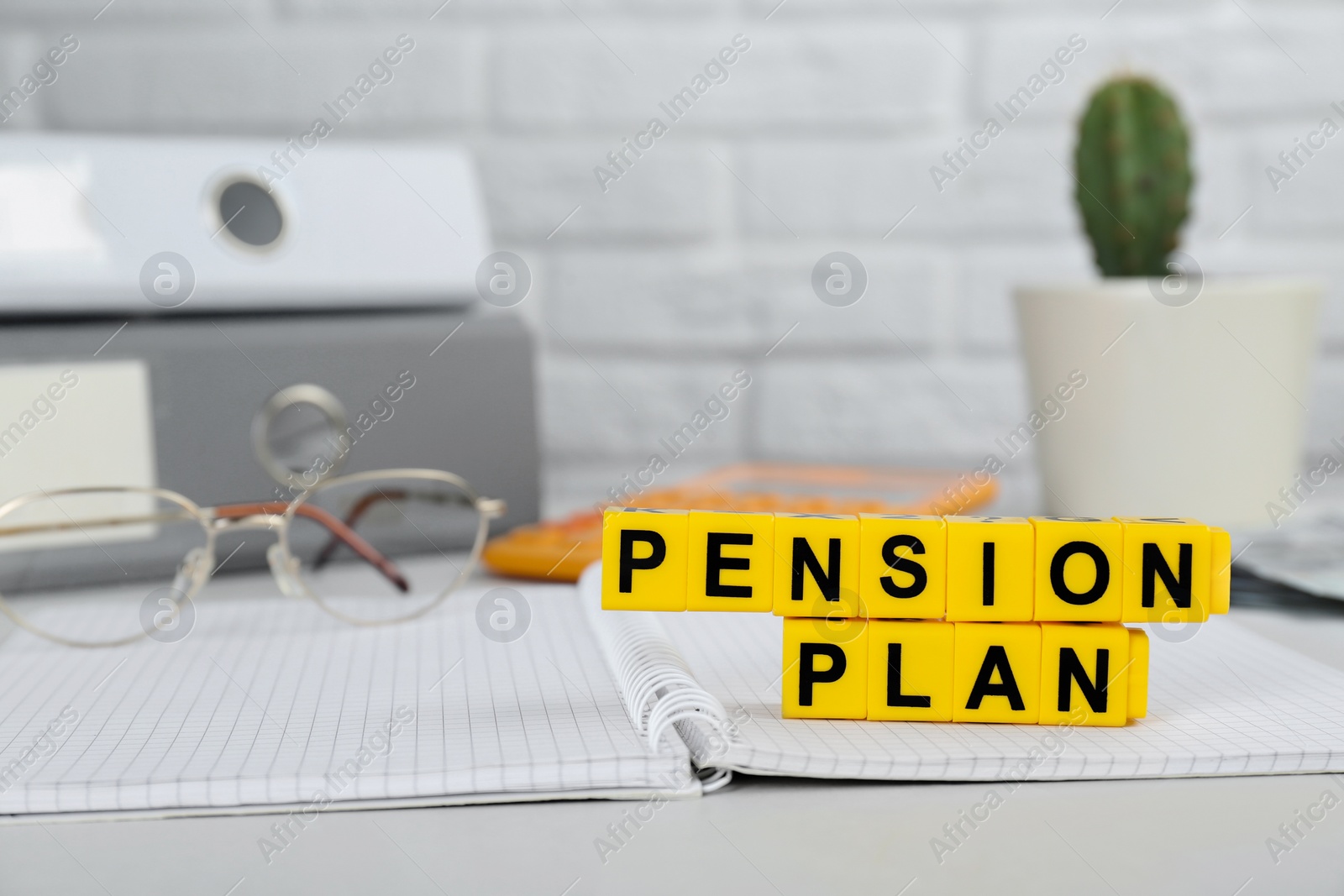 Photo of Yellow cubes with phrase Pension Plan and notebook on white office table