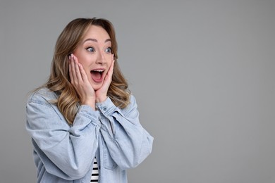 Portrait of happy surprised woman on grey background. Space for text