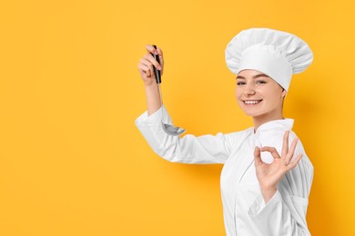 Photo of Professional chef with ladle showing OK gesture on yellow background. Space for text