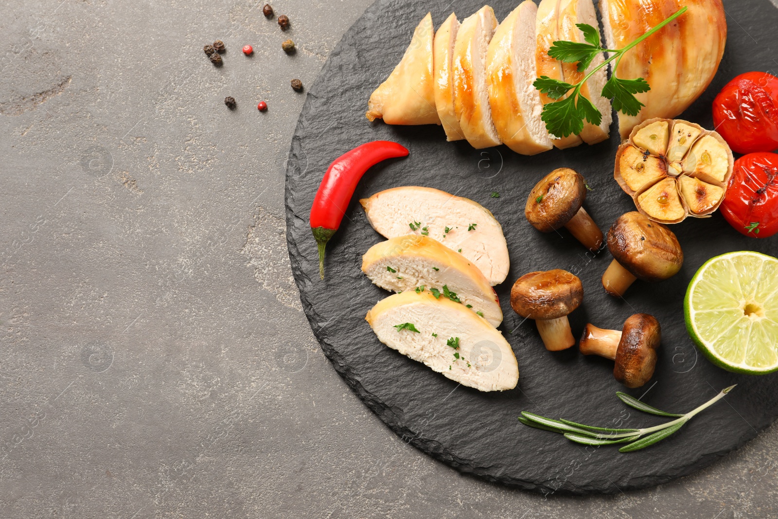 Photo of Fried chicken breasts served with garnish on grey background, top view. Space for text