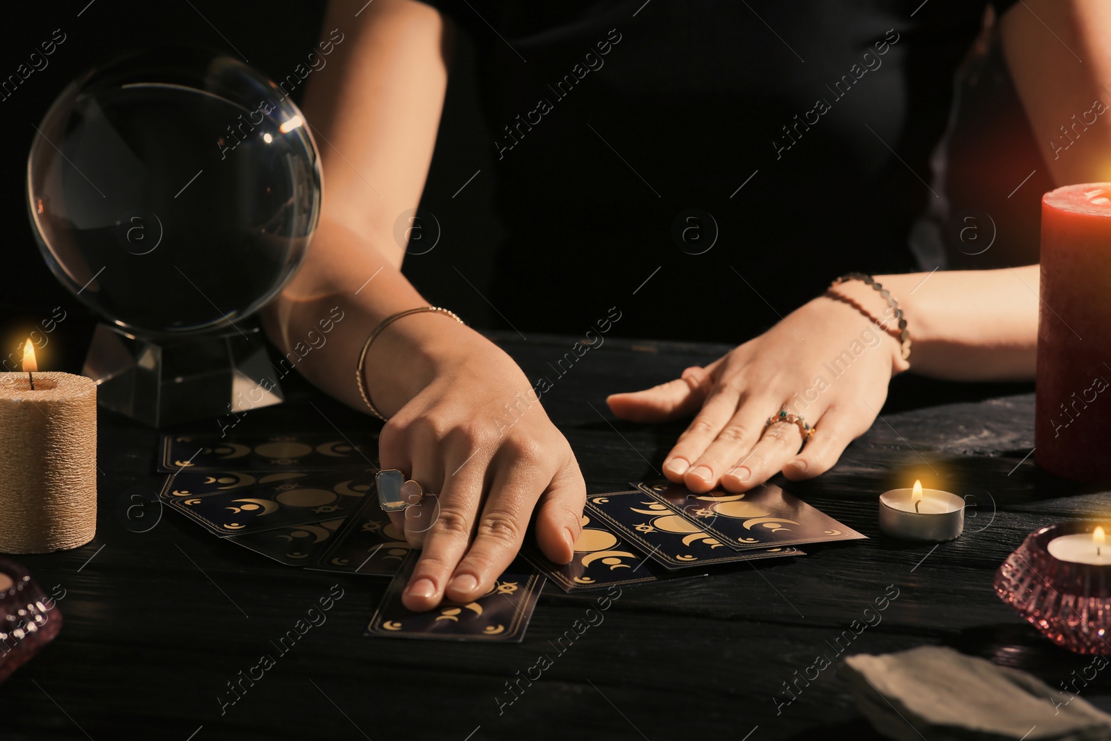 Photo of Soothsayer predicting future with tarot cards at table in darkness, closeup