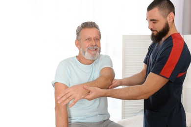 Photo of Physiotherapist working with patient in clinic. Rehabilitation therapy