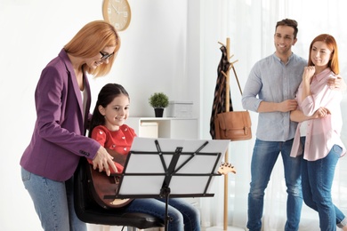 Little girl with her teacher and parents at music lesson. Learning notes