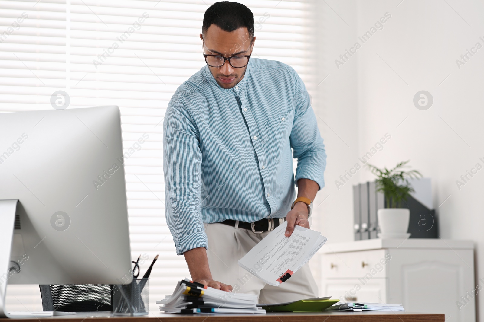 Photo of Young businessman working with documents at wooden table in office