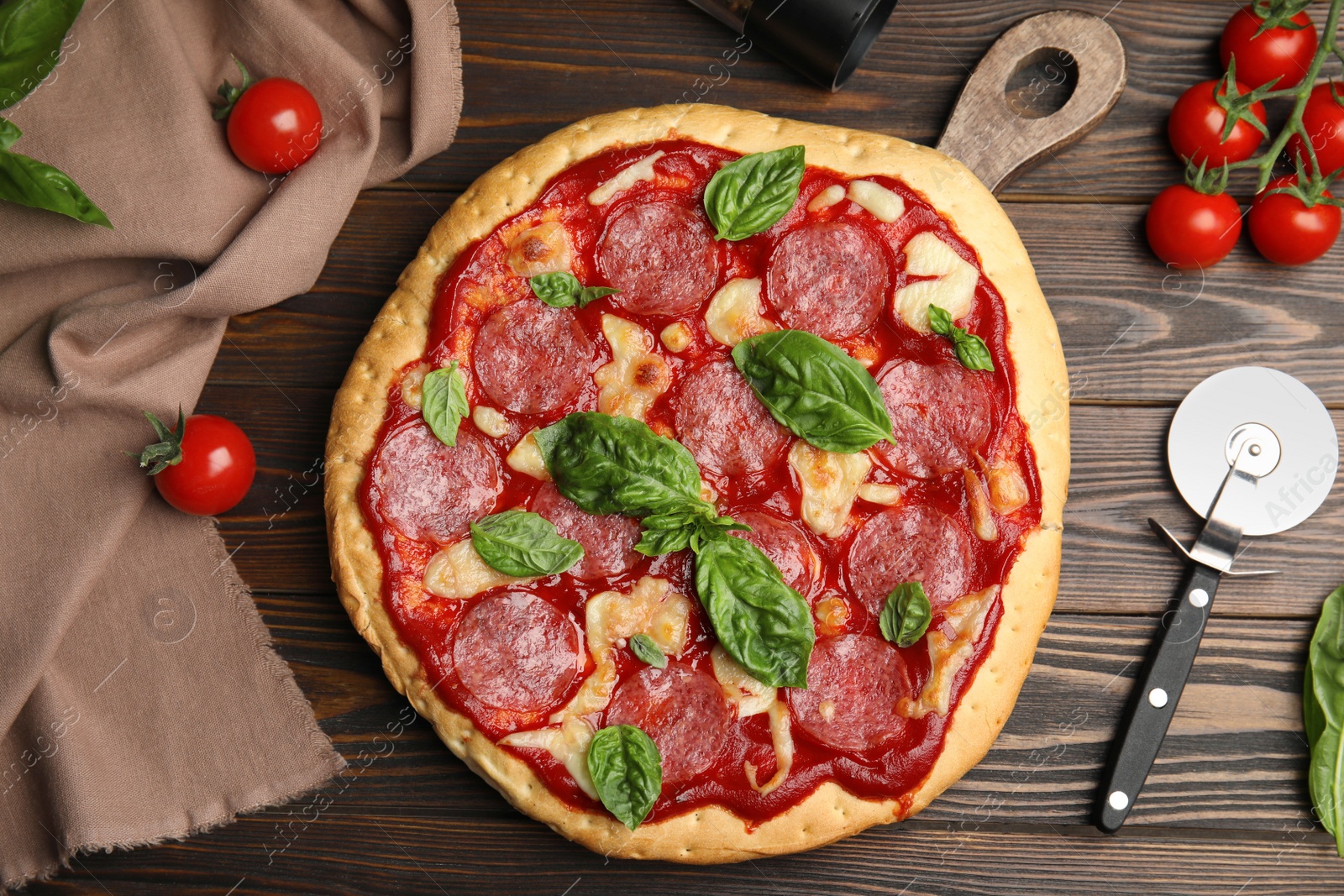 Photo of Pita pizza with pepperoni, cheese, basil and tomatoes on wooden table, flat lay