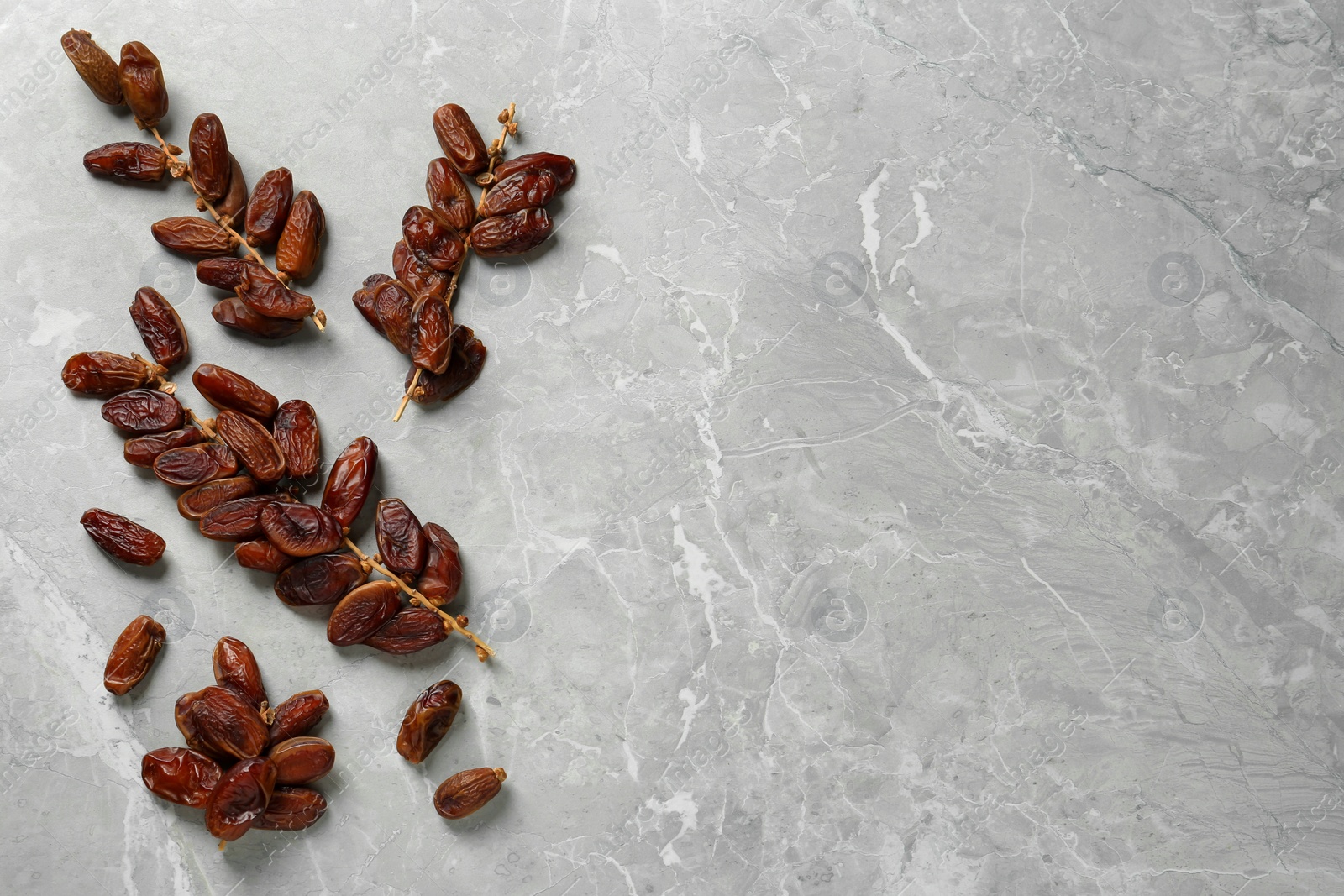 Photo of Branches with sweet dried dates on light table, flat lay. Space for text