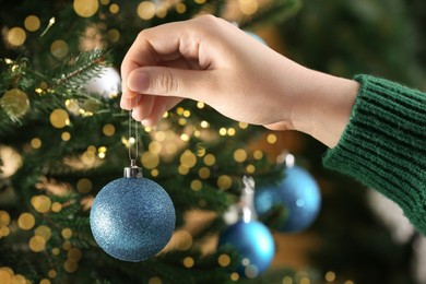 Woman decorating Christmas tree with beautiful bauble, closeup