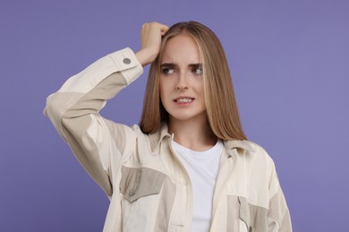 Portrait of embarrassed young woman on violet background