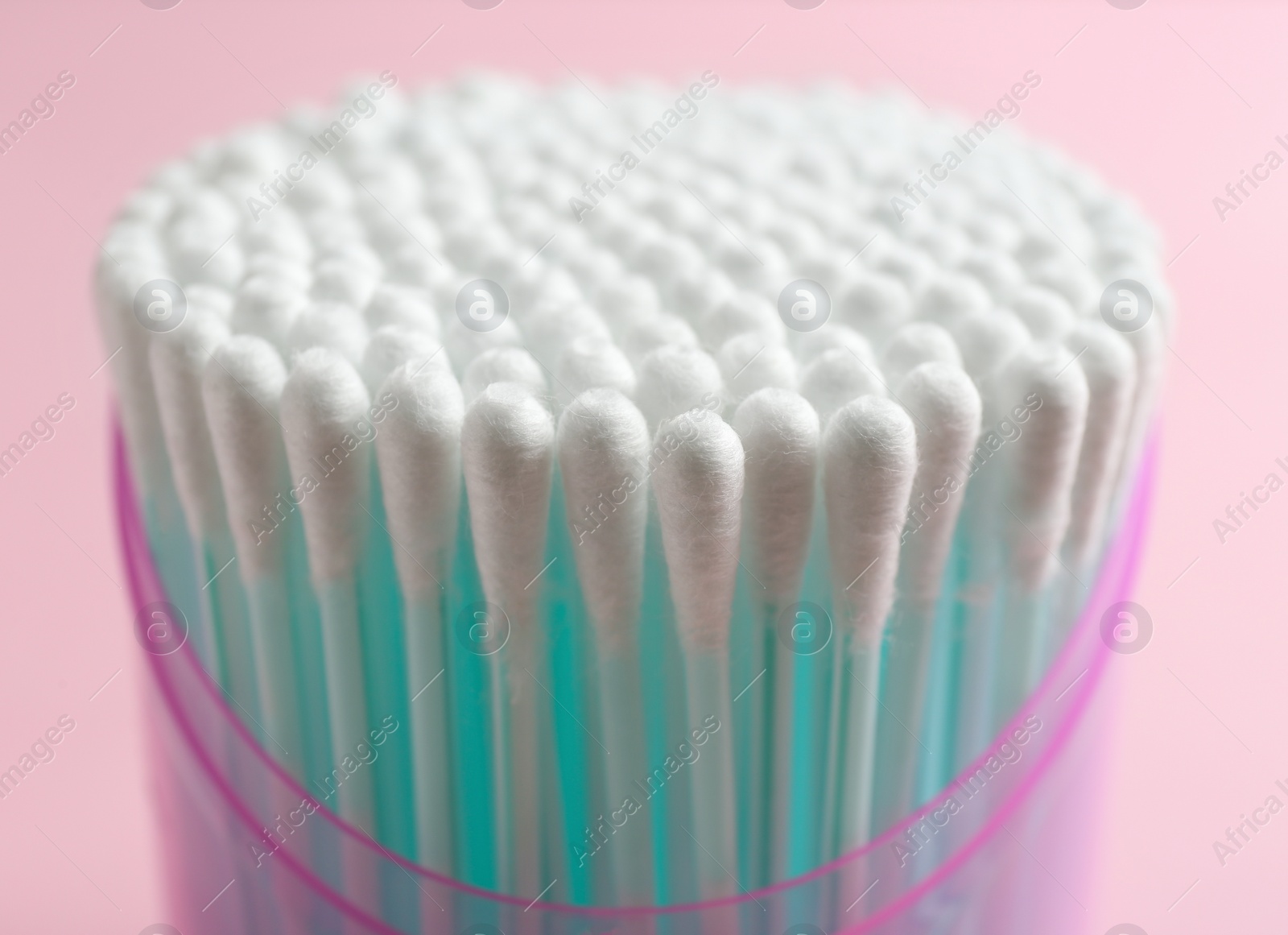 Photo of Plastic container with cotton swabs on color background, closeup