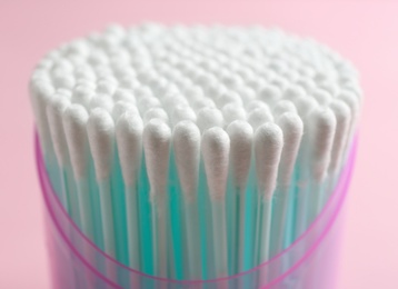 Photo of Plastic container with cotton swabs on color background, closeup