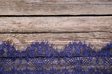 Photo of Beautiful lace on wooden table, top view. Space for text