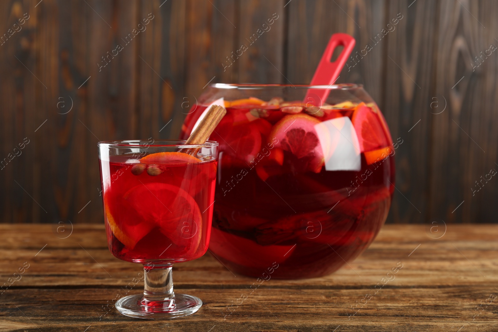 Photo of Glass and bowl with aromatic punch drink on wooden table