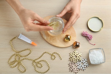 Photo of Woman making beautiful snow globe at wooden table, top view