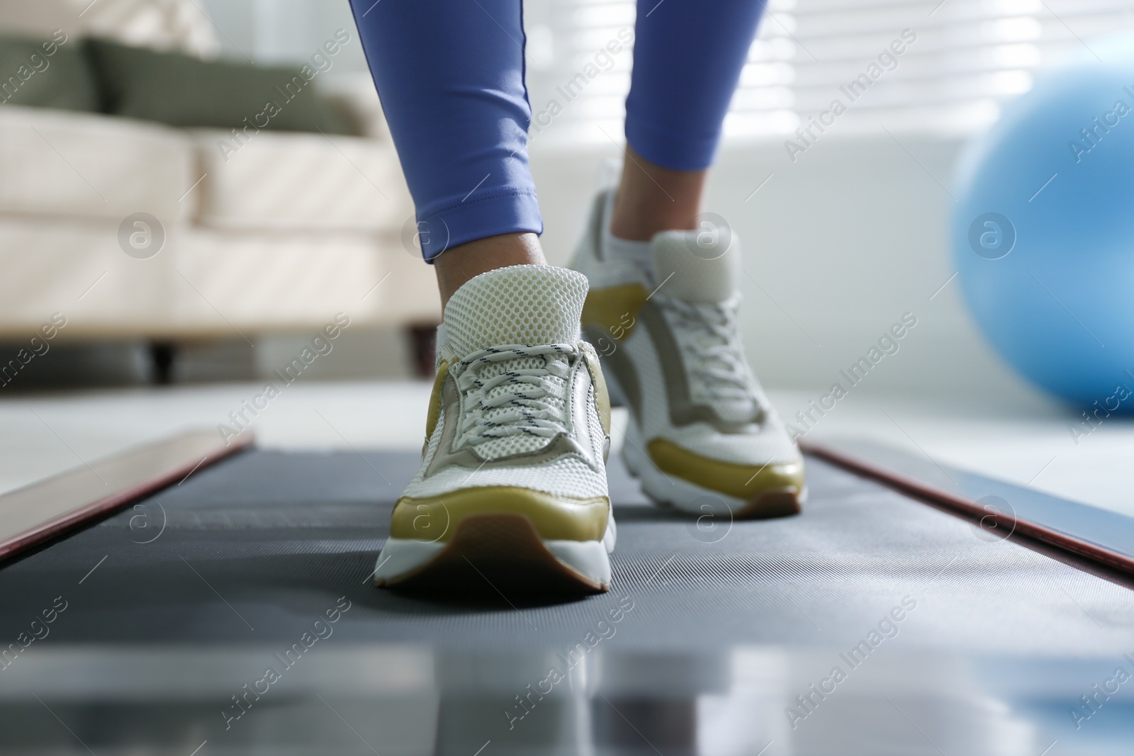 Photo of Woman training on walking treadmill at home, closeup