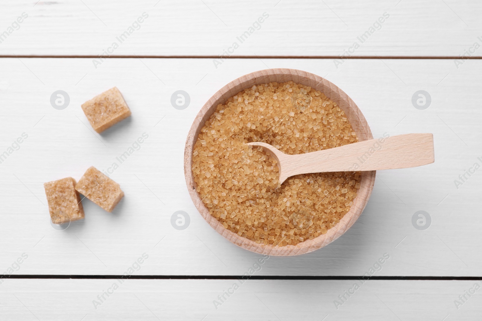 Photo of Bowl and spoon with brown sugar on white wooden table, top view