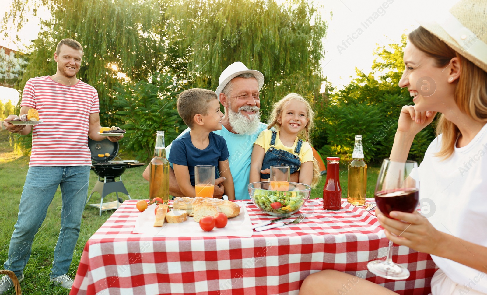 Photo of Happy family having barbecue in park on sunny day