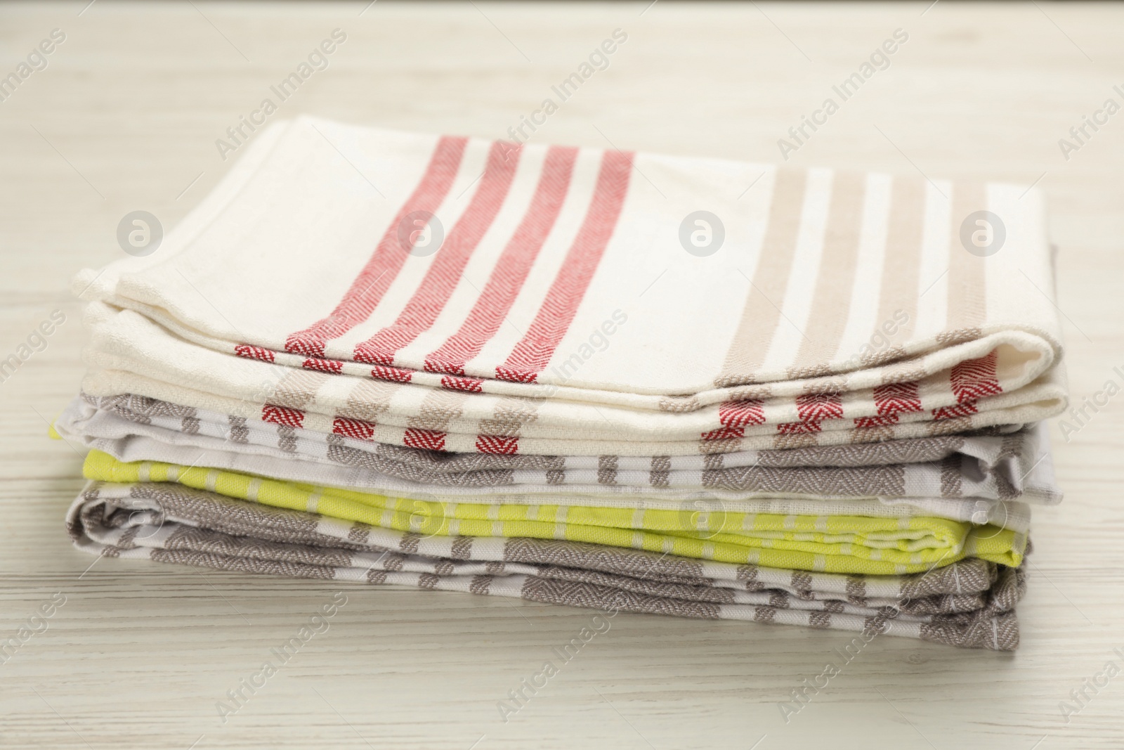 Photo of Stacked kitchen towels on white wooden table, closeup