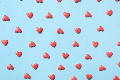 Photo of Pink heart shaped sprinkles on light blue background, flat lay