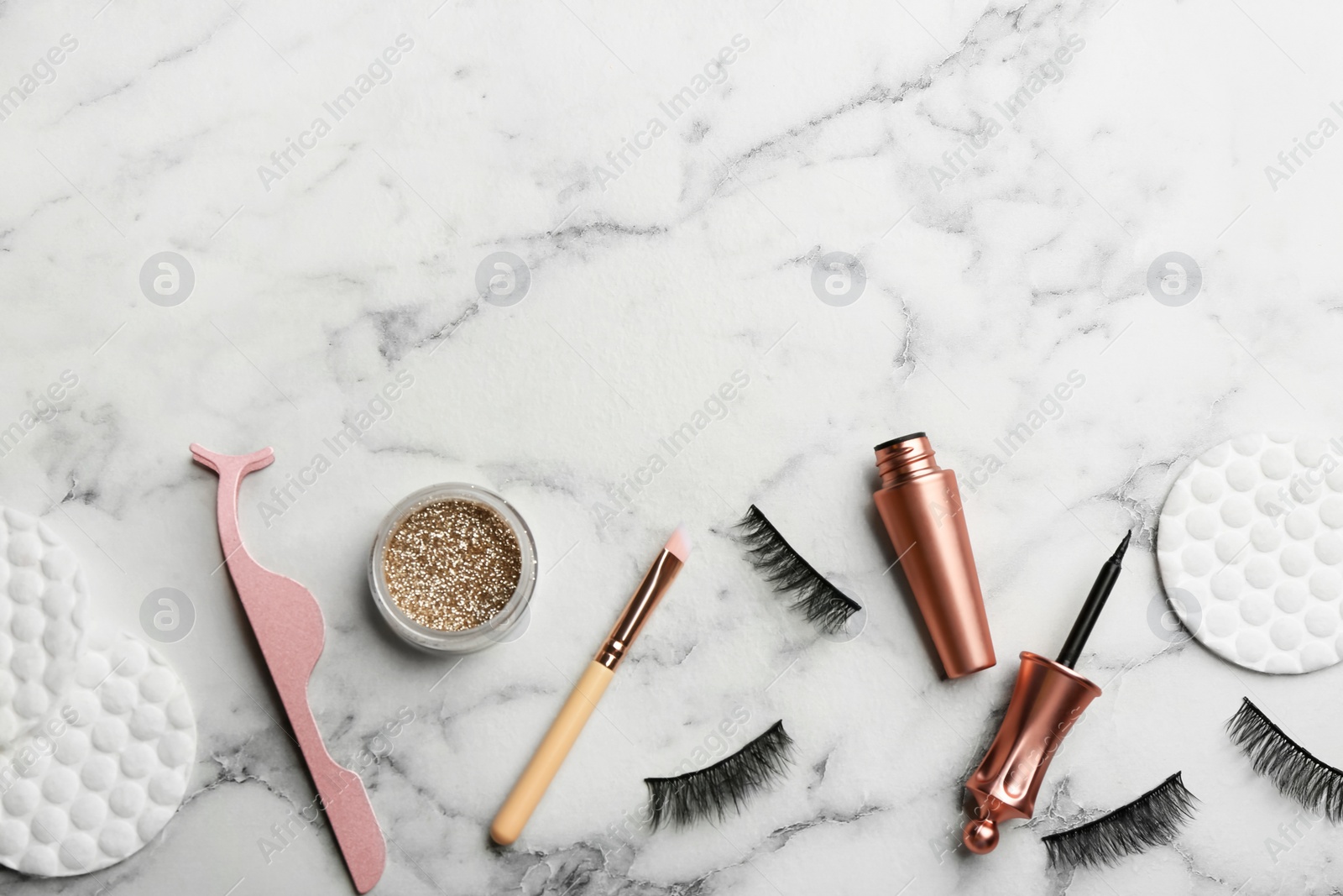 Photo of Flat lay composition with magnetic eyelashes and accessories on white marble table. Space for text