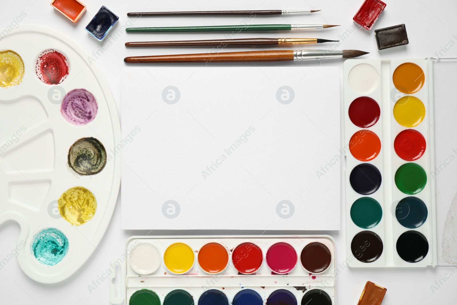 Photo of Watercolor paints, brushes and blank paper with space for design on white background, flat lay