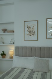 Photo of Large bed, pictures and shelves with accessories in stylish bedroom