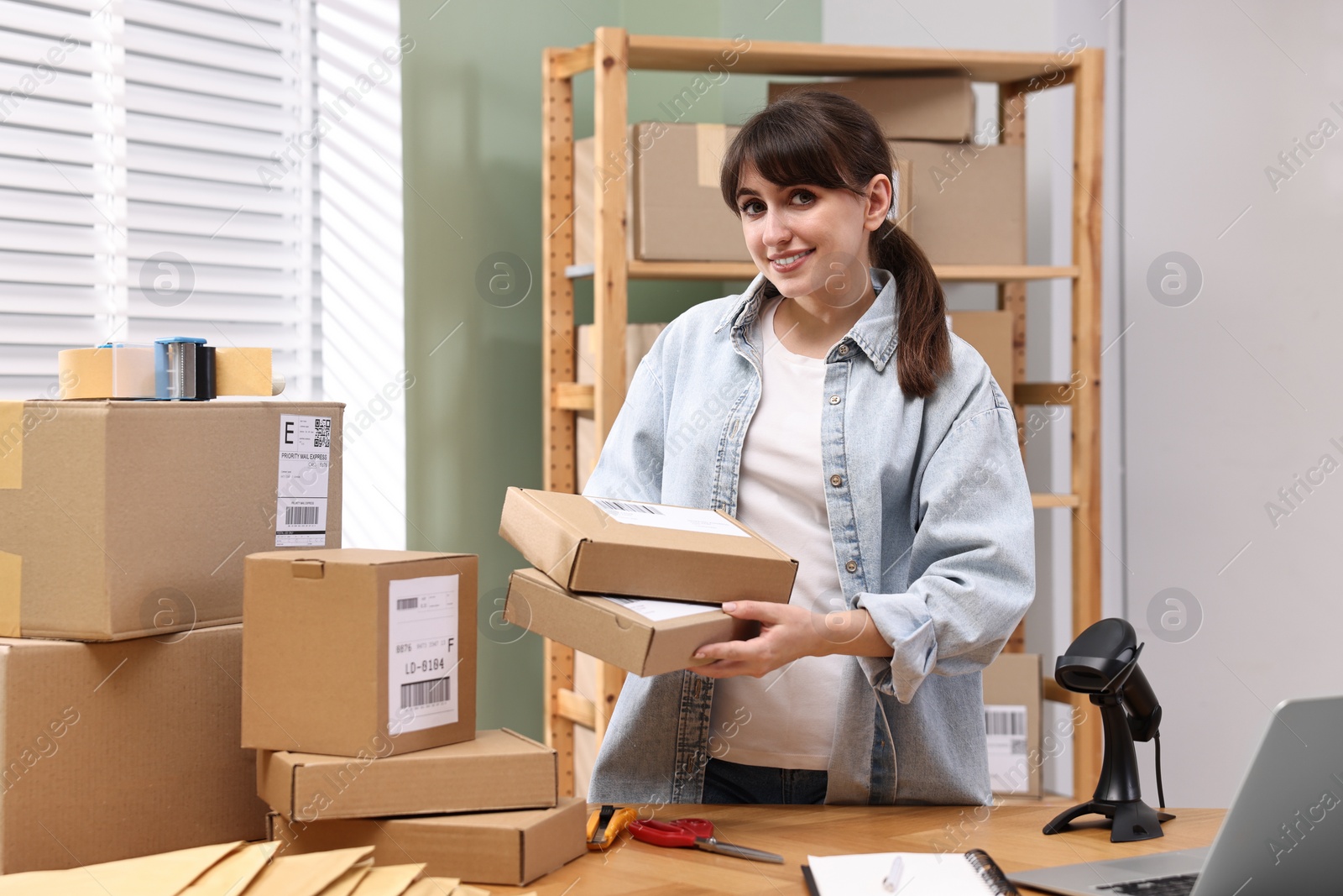 Photo of Parcel packing. Post office worker with parcels at wooden table indoors