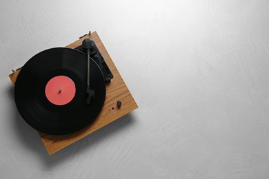 Turntable with vinyl record on light background, top view. Space for text