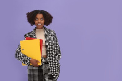 Photo of Smiling African American intern with folders on purple background. Space for text