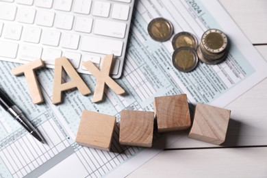 Photo of Tax accounting. Cubes with numbers 2024, document, keyboard, coins and pen on white wooden table, flat lay