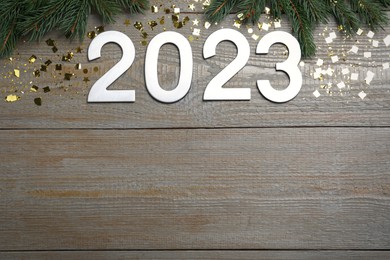 Photo of Flat lay composition with number 2023 and festive decor on wooden background, space for text. Happy New Year