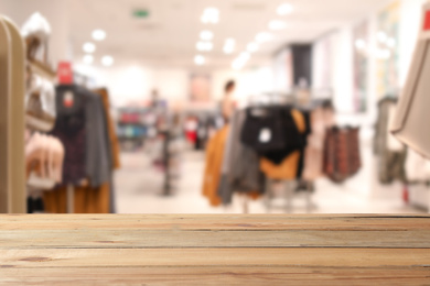 Image of Empty wooden table and blurred view of store with modern clothes