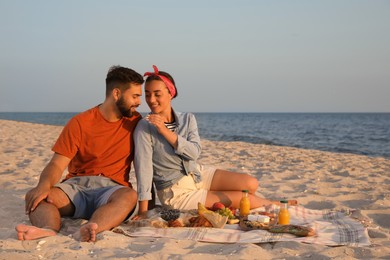 Photo of Lovely couple having picnic on sandy beach near sea