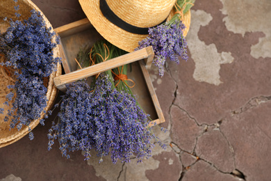 Photo of Beautiful lavender flowers and straw hat on cement floor outdoors, flat lay. Space for text