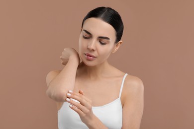 Photo of Woman with dry skin checking her elbow on beige background