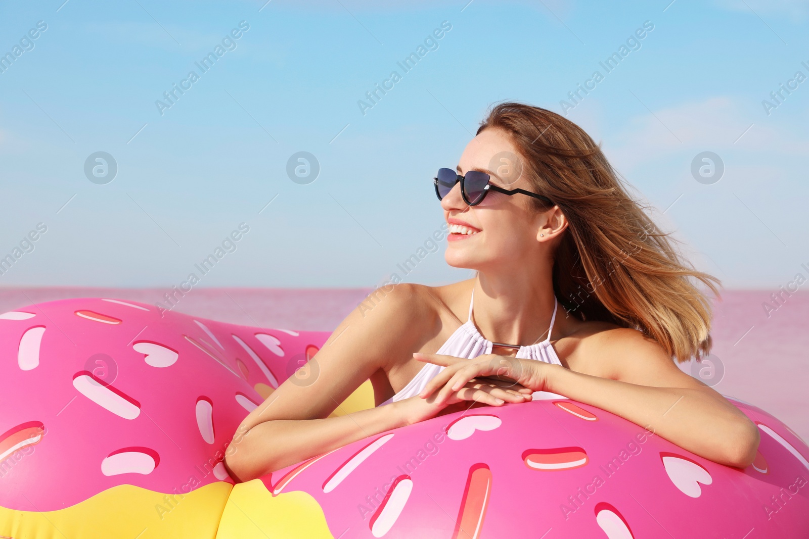 Photo of Beautiful woman with inflatable ring near pink lake