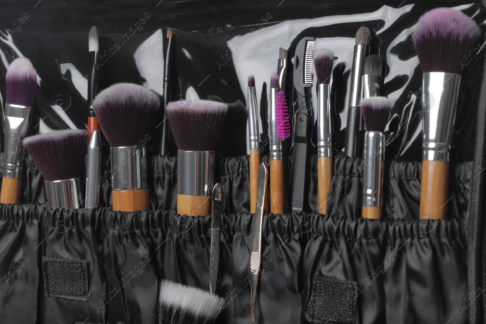 Photo of Stylish case with tweezers and brushes for applying makeup products, closeup