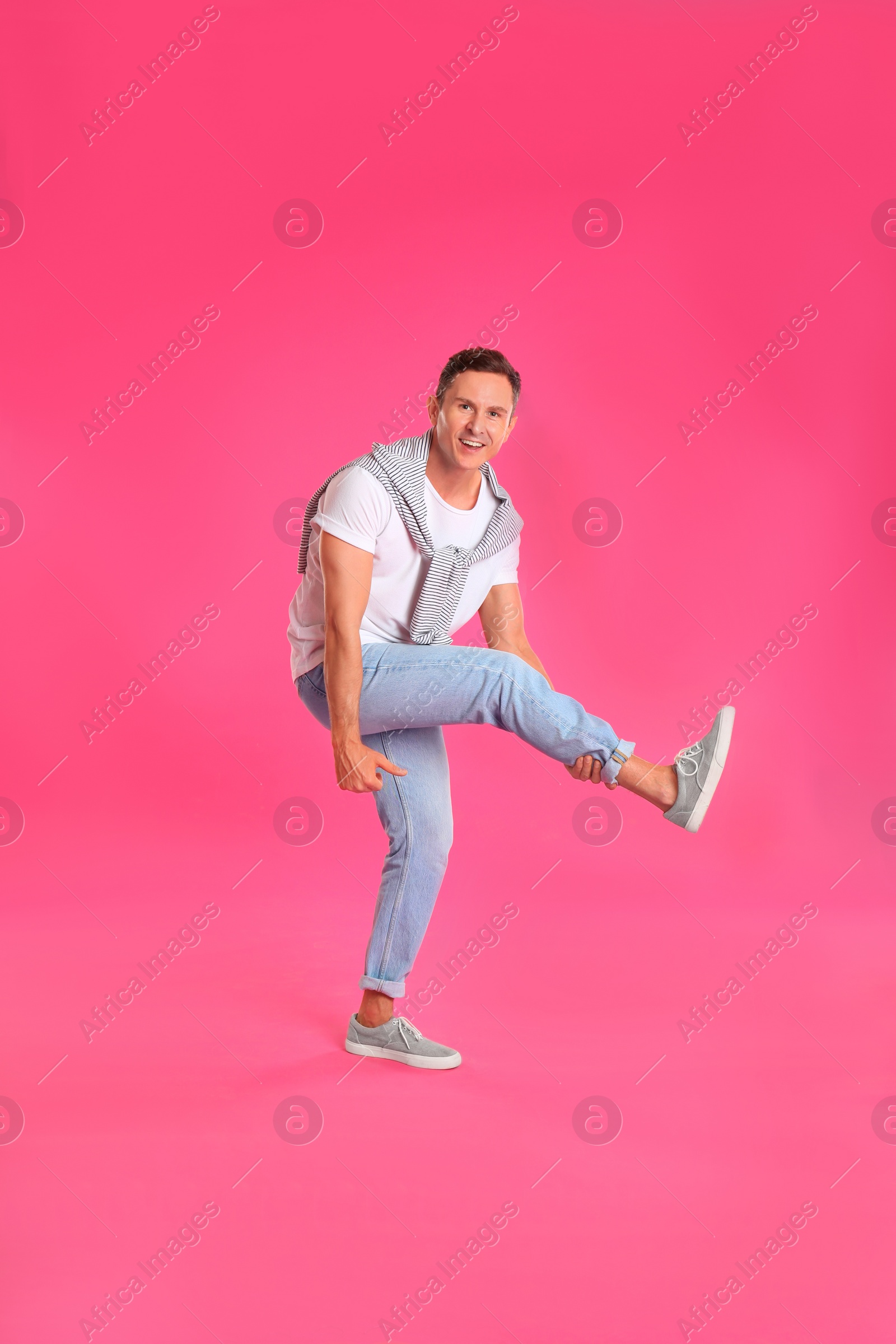 Photo of Happy attractive man dancing on pink background