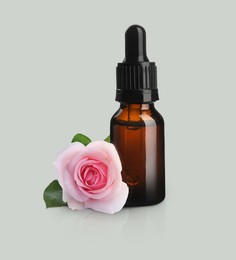 Image of Bottle of rose essential oil and flower on light background