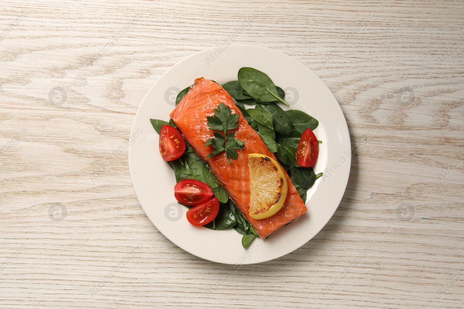 Photo of Tasty grilled salmon with tomatoes, lemon and basil on white wooden table, top view