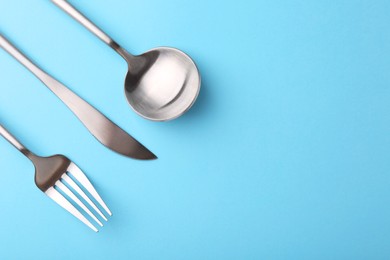 Photo of Stylish cutlery set on light blue table, flat lay. Space for text