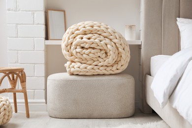 Photo of Soft chunky knit blanket on ottoman in stylish room interior