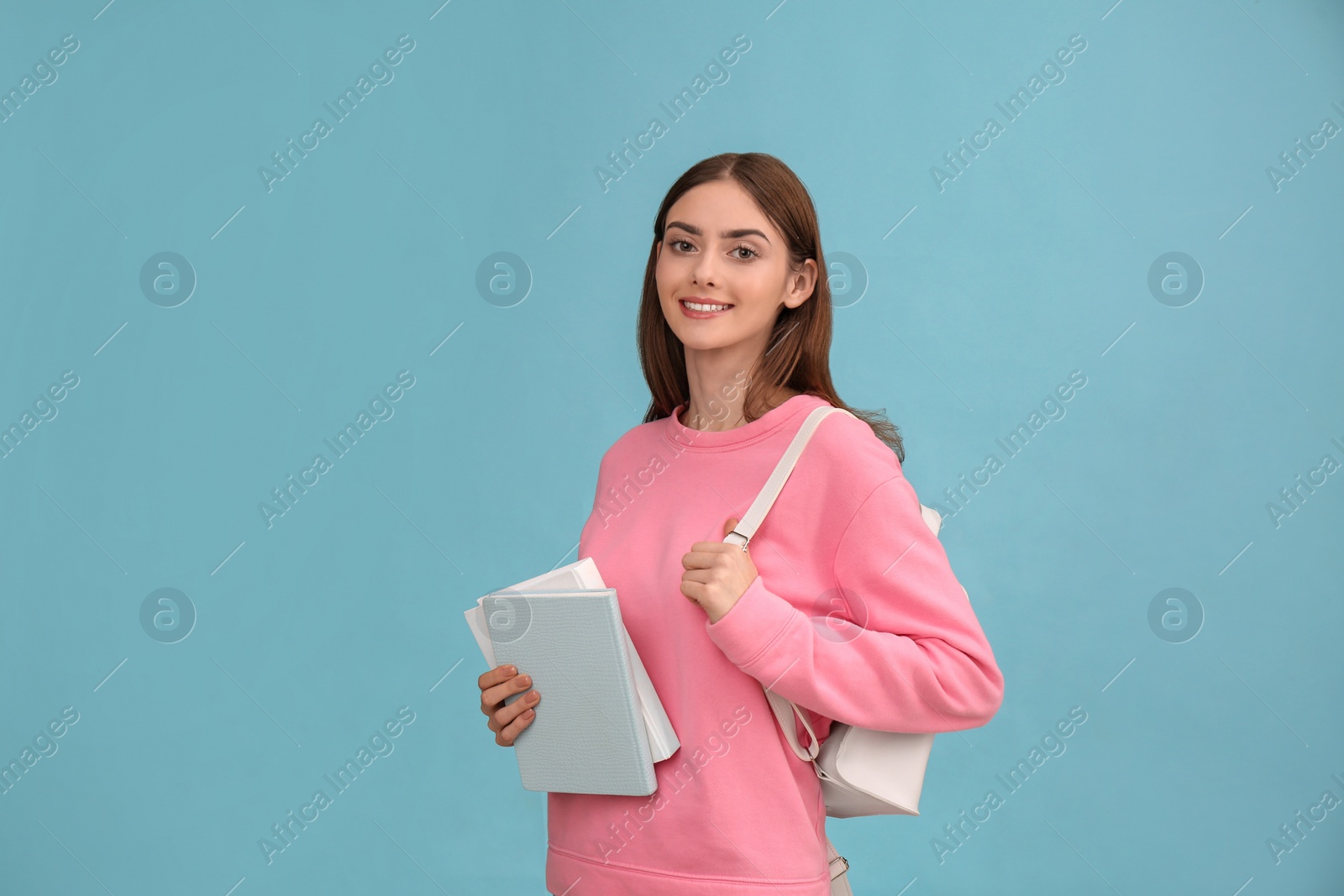 Photo of Teenage student with books and backpack on turquoise background