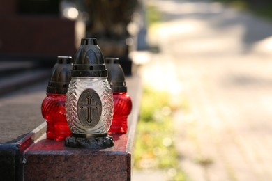 Grave lanterns on granite surface in cemetery, space for text