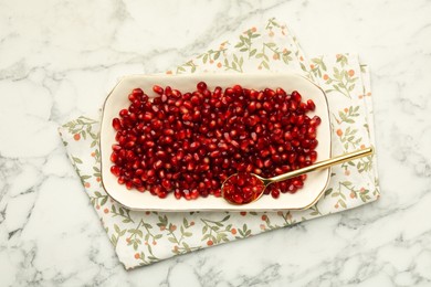Photo of Ripe juicy pomegranate grains on white marble table, top view