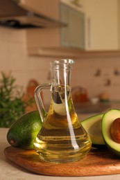 Fresh avocados and jug of cooking oil on beige marble table in kitchen