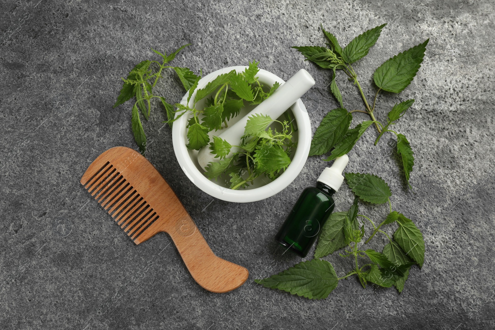 Photo of Stinging nettle, extract and comb on grey background, flat lay. Natural hair care