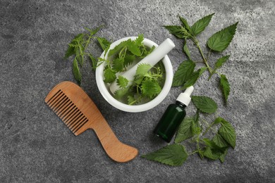 Stinging nettle, extract and comb on grey background, flat lay. Natural hair care