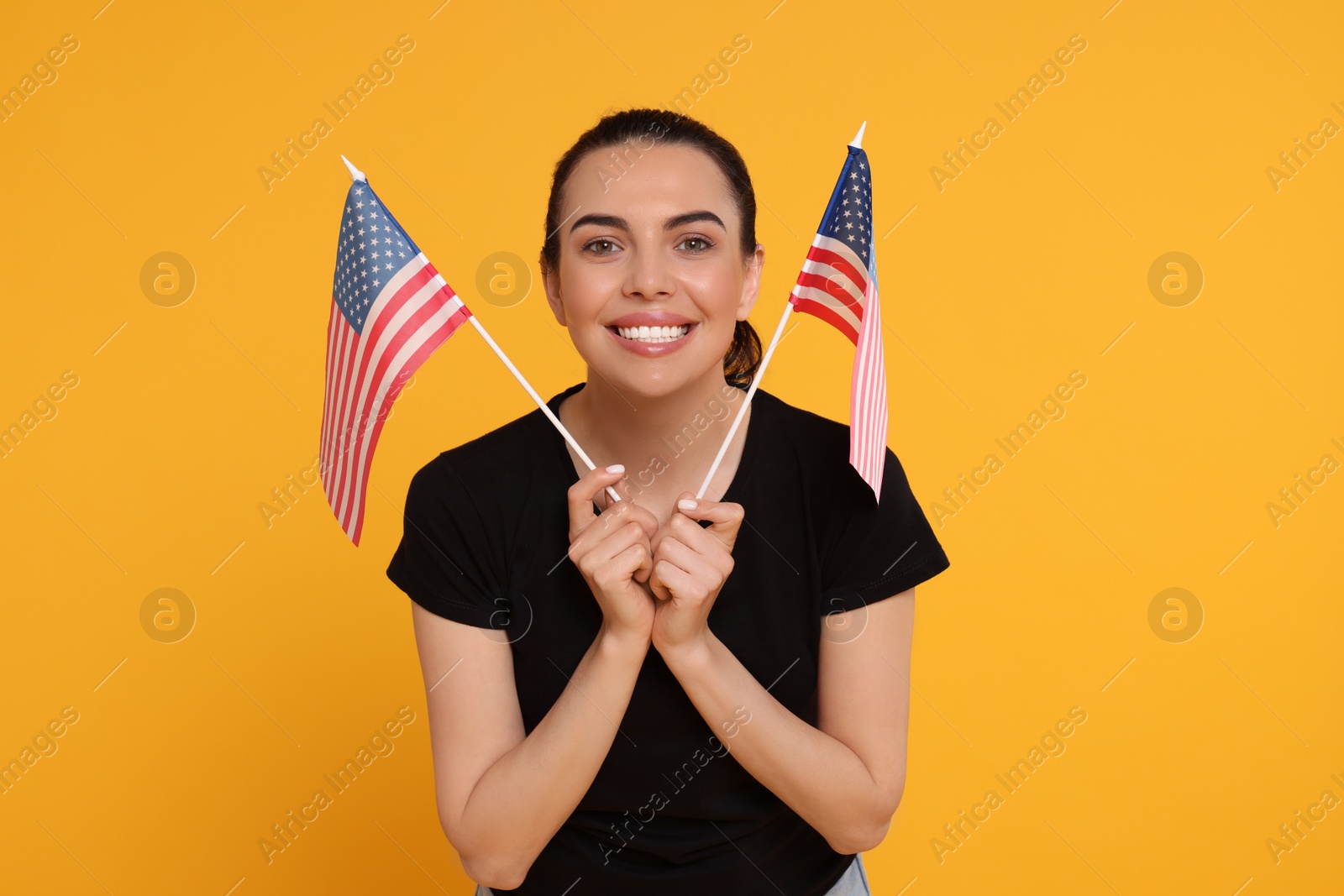 Photo of 4th of July - Independence Day of USA. Happy woman with American flags on yellow background