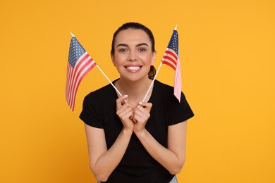 4th of July - Independence Day of USA. Happy woman with American flags on yellow background