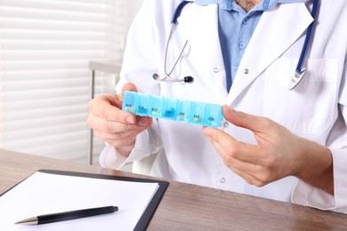 Doctor holding box of pills in clinic, closeup. Patient consultation